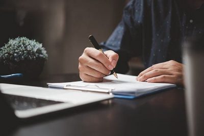 hand-holding-pen-writing-paperwork-business-document-financial-investment-signature-contract-job-insurance-desk